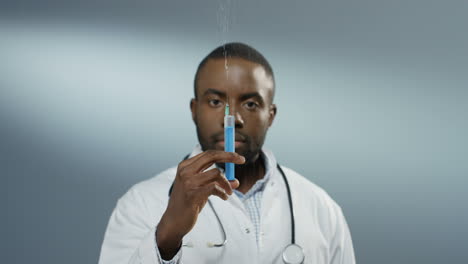 Close-up-of-the-young-African-American-man-physician-or-intern-holding-a-syringe-with-a-needle-and-withdrawing-fluid.